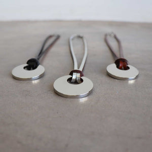 Silver Moon-shaped pendant combined with a natural leather band, available in 3 colours, Black, Silver and Tan.