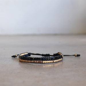 Classic art deco styling, featuring two rows of fine brass and glass beads all hand-knotted using traditional ethnic techniques. Gold & Black.