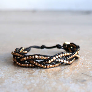 Three-strand, hand-knotted, metallic bead bracelet. Button style closure with 3 size options. Black/Gold.