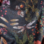 Close-up of a fabric with floral and insect pattern on a dark background