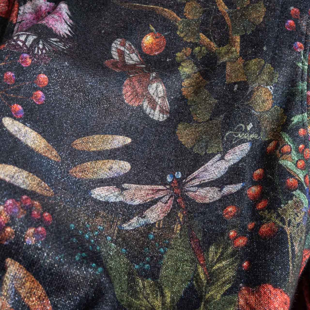 Close-up of a fabric with floral and insect pattern on a dark background