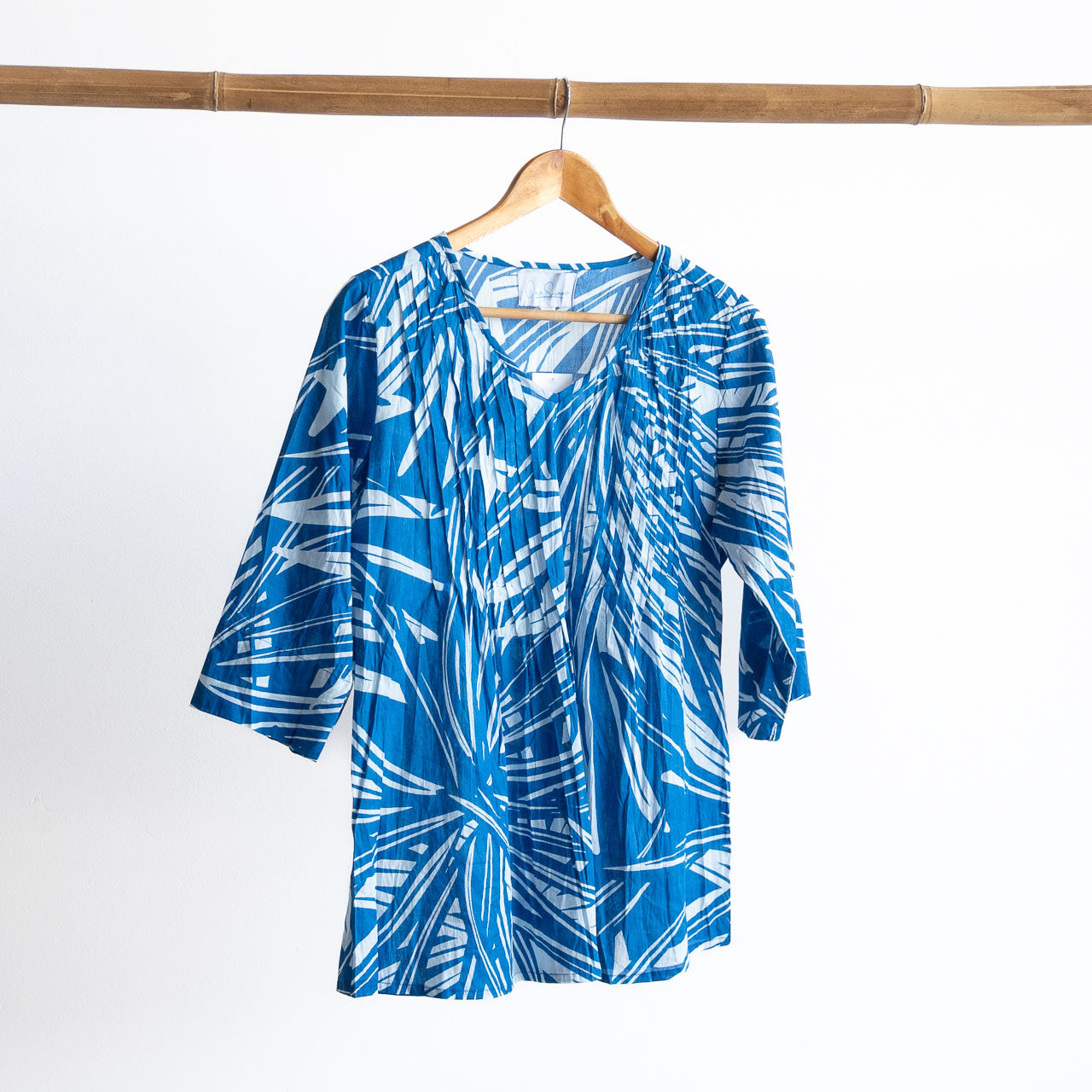 Blue and white patterned shirt on a wooden hanger against a white background