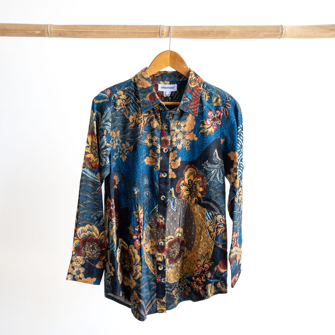 Floral patterned shirt on a wooden hanger against a white background
