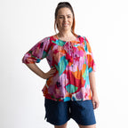 Woman wearing a colorful artwork floral light cotton blouse