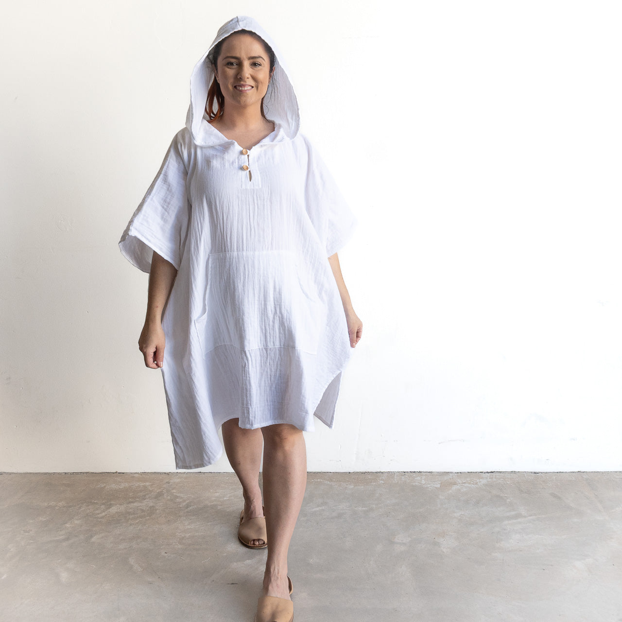 White poncho-style hoodie dress in lightweight fabric, features short sleeves and front buttons.