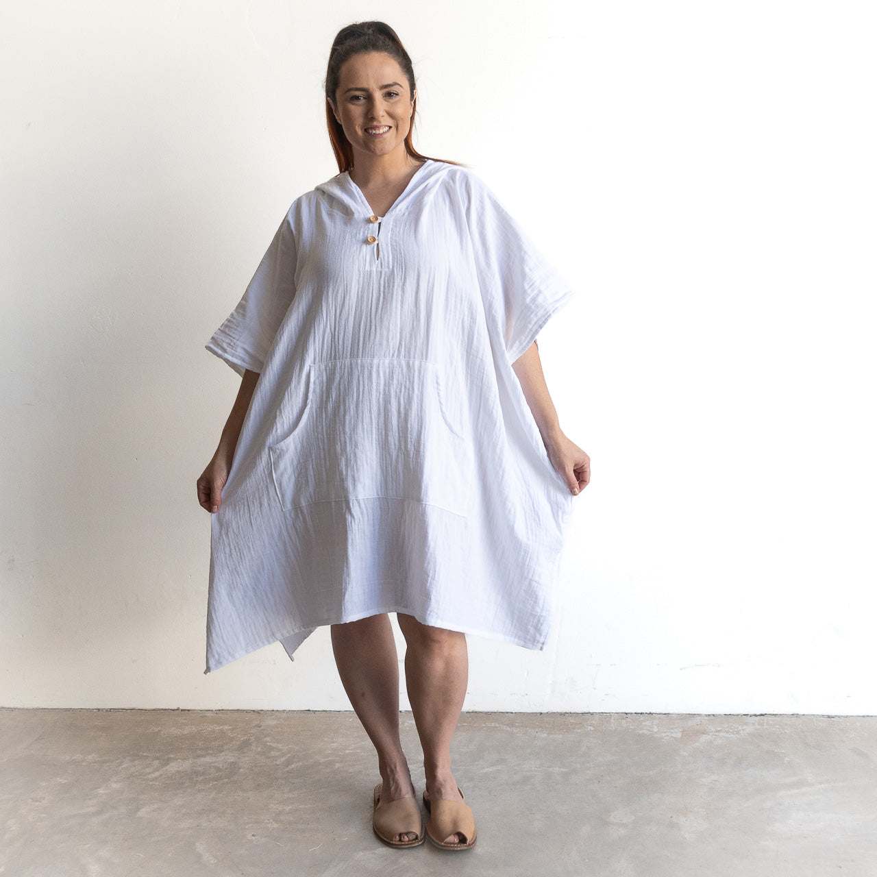 Noosa Beach Hoodie, a loose knee-length cotton poncho dress in solid colour with wide sleeves and front pockets; worn with flats.