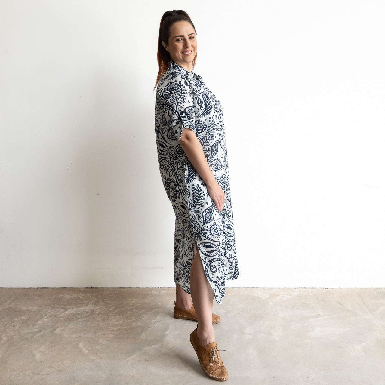 Button-through classic cotton shirt dress in navy and white illustrated botanical print. Midi length hemline.