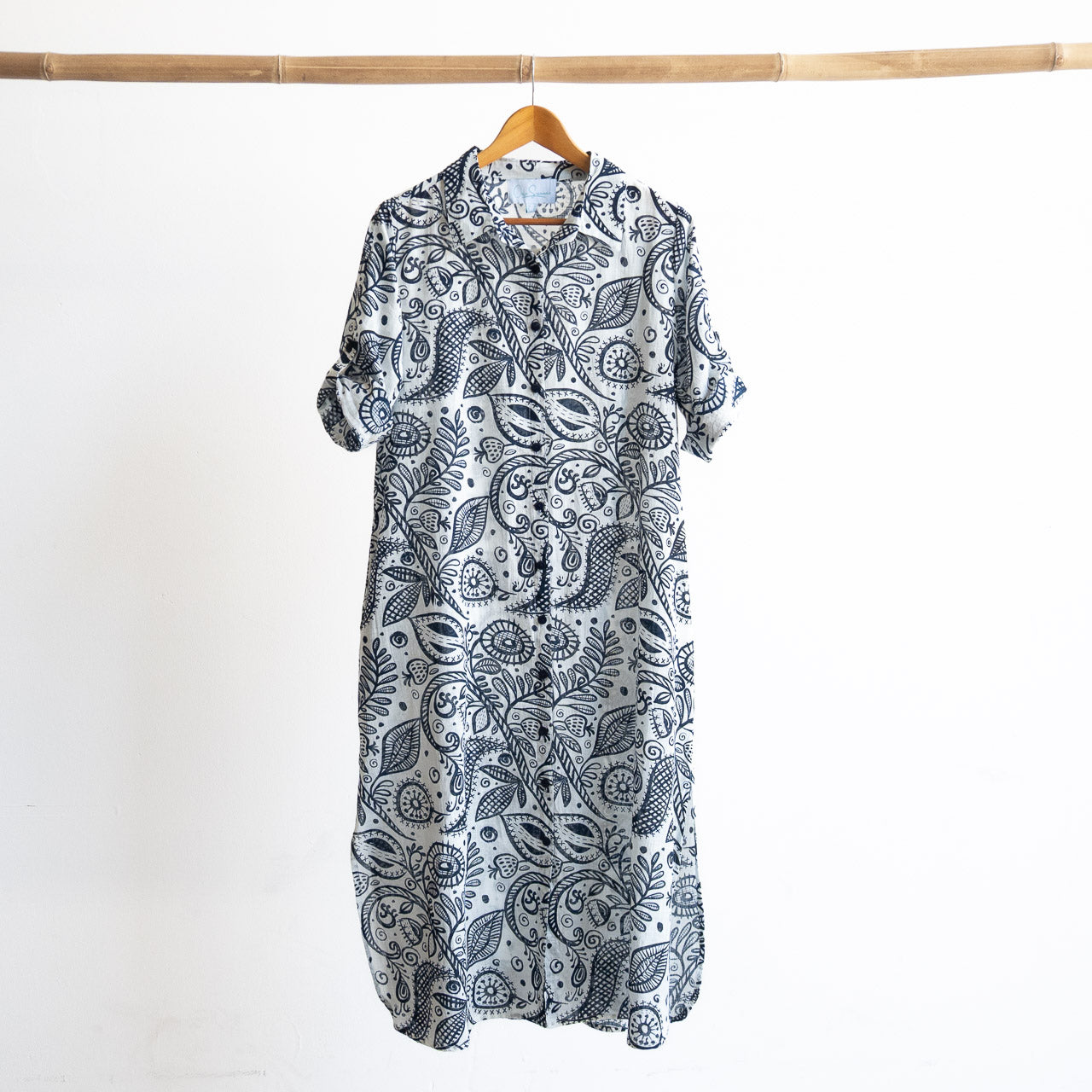 Button-through classic collared cotton shirt dress in navy and white illustrated botanical print. Midi length hemline.
