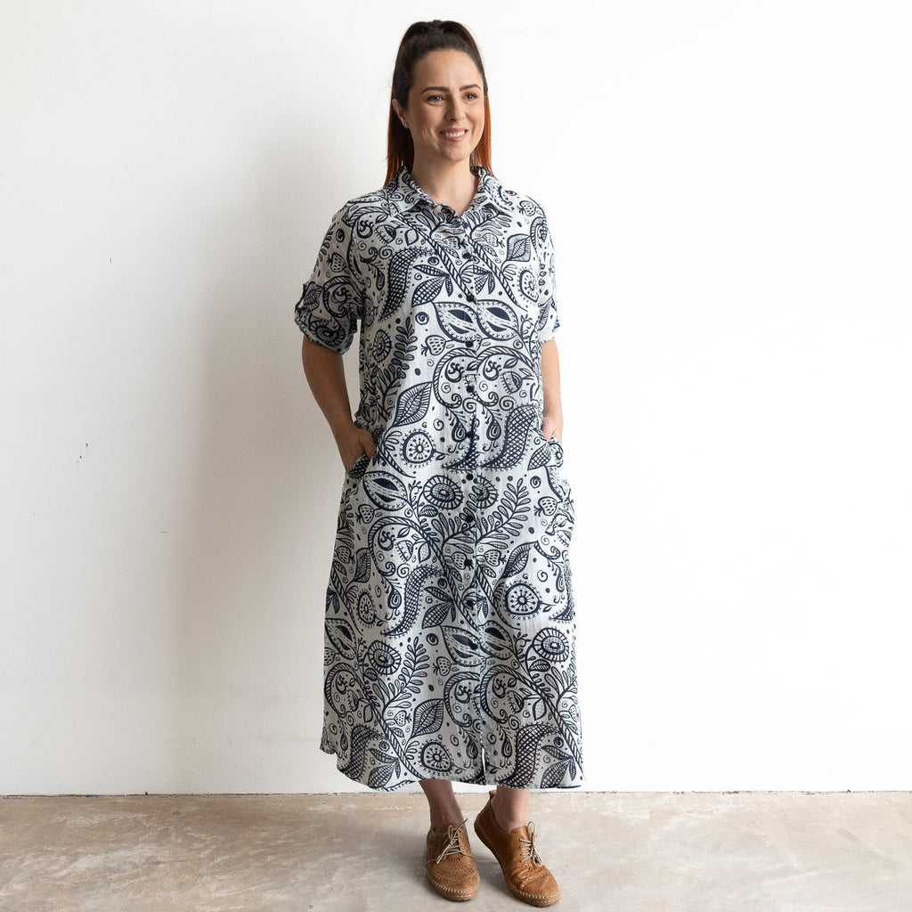 Button-through classic collared cotton shirt dress in navy and white illustrated botanical print. Midi length hemline.