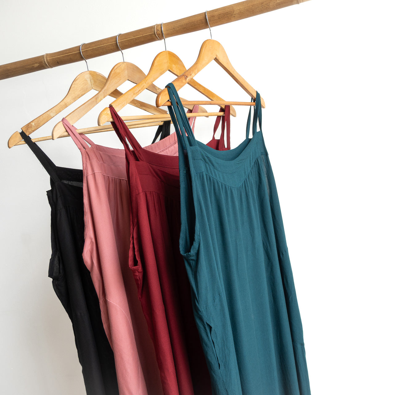 Shoestring midi sundress colour range hanging on a bamboo pole.