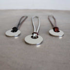 Silver Moon-shaped pendant combined with a natural leather band, available in 3 colours, Black, Silver and Tan.