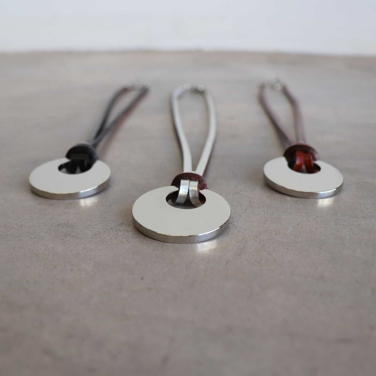 Silver Moon-shaped pendant combined with a natural leather band, available in 3 colours, Black, Silver and Tan.
