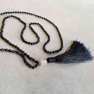 Glass faceted beads with metallic finish. Silver plated Buddha bead charm at centre with long, silky soft tassel. BLACK