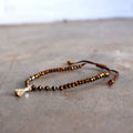 Threaded bracelet with cut glass beads featuring fine, mini tassel. Great for stacking or individual wearing. Slide-knot adjustable closure provides sizing flexibility. Bronze.