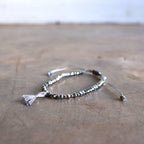 Threaded bracelet with cut glass beads featuring fine, mini tassel. Great for stacking or individual wearing. Slide-knot adjustable closure provides sizing flexibility. Silver.