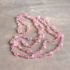 Stunning luxe-length, hand-knotted necklace made with faceted glass beads in a rainbow metallic finish. Champagne Pink.