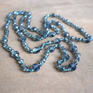 Stunning luxe-length, hand-knotted necklace made with faceted glass beads in a rainbow metallic finish. Denim Blue.