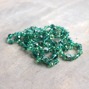 Stunning luxe-length, hand-knotted necklace made with faceted glass beads in a rainbow metallic finish. Emerald Green.
