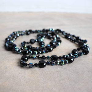 Stunning luxe-length, hand-knotted necklace made with faceted glass beads in a rainbow metallic finish. Midnight Black.
