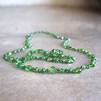 Stunning luxe-length, hand-knotted necklace made with faceted glass beads in a rainbow metallic finish. Ocean Green.