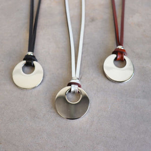 Silver Moon-shaped pendant combined with a natural leather band, available in 3 colours, Black, Silver and Tan.