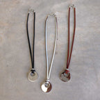 Silver Moon-shaped pendant combined with a natural leather band, available in 3 colours, Black, Silver and Tan.