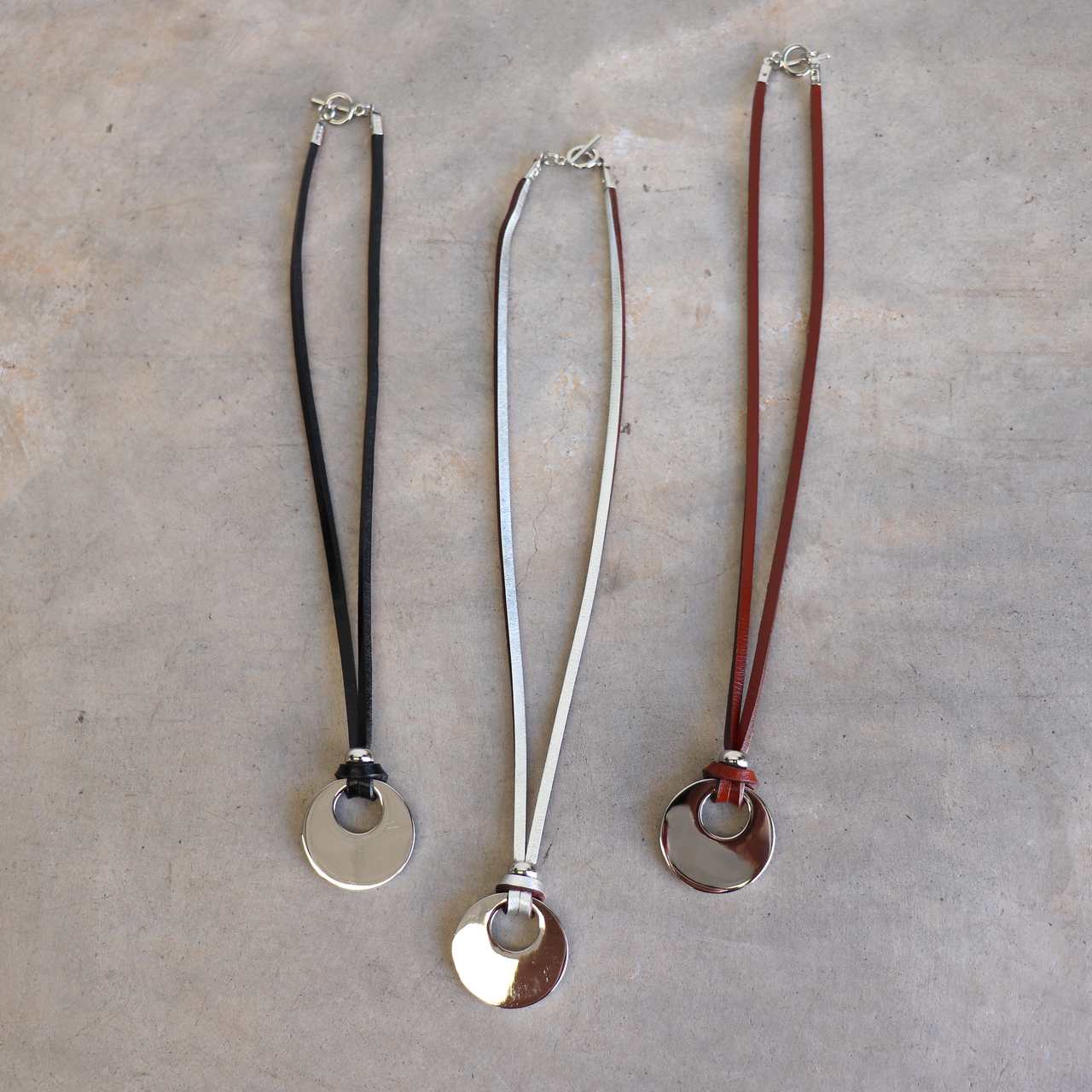 Silver Moon-shaped pendant combined with a natural leather band, available in 3 colours, Black, Silver and Tan.