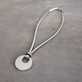 Silver Moon-shaped pendant combined with a natural leather band, available in 3 colours, Black, Silver and Tan.