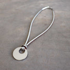 Silver Moon-shaped pendant combined with a natural leather band, available in 3 colours, Black, Silver and Tan.