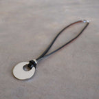 Silver Moon-shaped pendant combined with a natural leather band, available in 3 colours, Black, Silver and Tan.