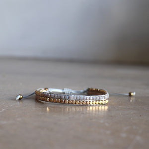 Classic art deco styling, featuring two rows of fine brass and glass beads all hand-knotted using traditional ethnic techniques. Gold & Grey.