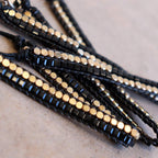 Classic art deco styling, featuring two rows of fine brass and glass beads all hand-knotted using traditional ethnic techniques. Gold & Black.