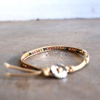 Handmade bracelet with fine metallic beads. Two colour options for stacking or individual wearing. Button style closure with 3 size options. Beige/Mix.