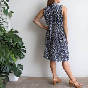 Origami Dress in floral print is a sleeveless trapeze sundress in black or navy blue. Back view.