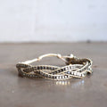 Three-strand, hand-knotted, metallic bead bracelet. Button style closure with 3 size options. Natural/Silver.