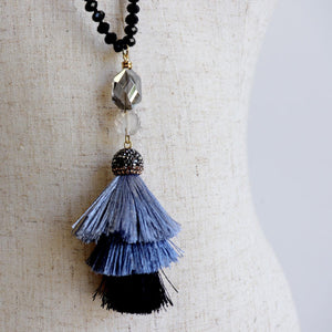 Zeta Necklace is handknotted with cut glass beads and features a tiered tassel pendant in smokey greys.